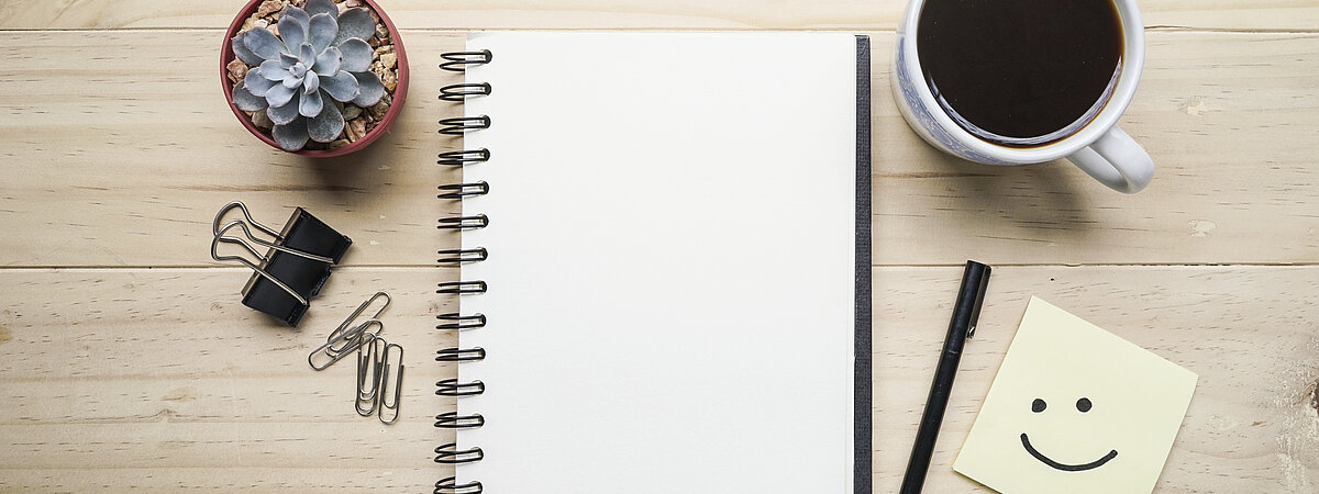 Call_for_Papers_Slider Blick von oben auf einen Schreibtisch mit Schreibutensilien und Kaffee